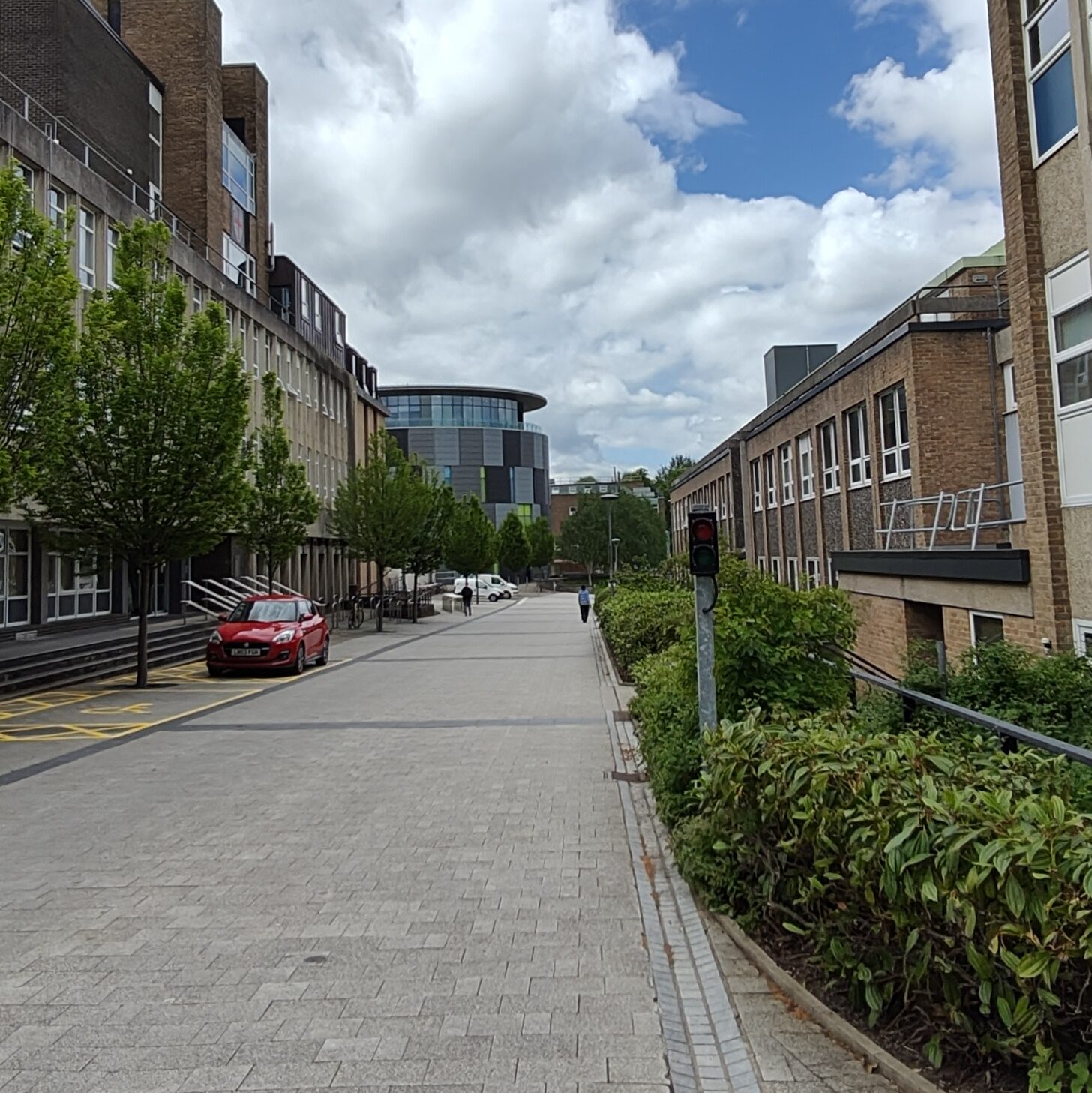 Straight stone-tiled path with red-bricked buildings on the right and brown pebble-dashed buildings on the left.