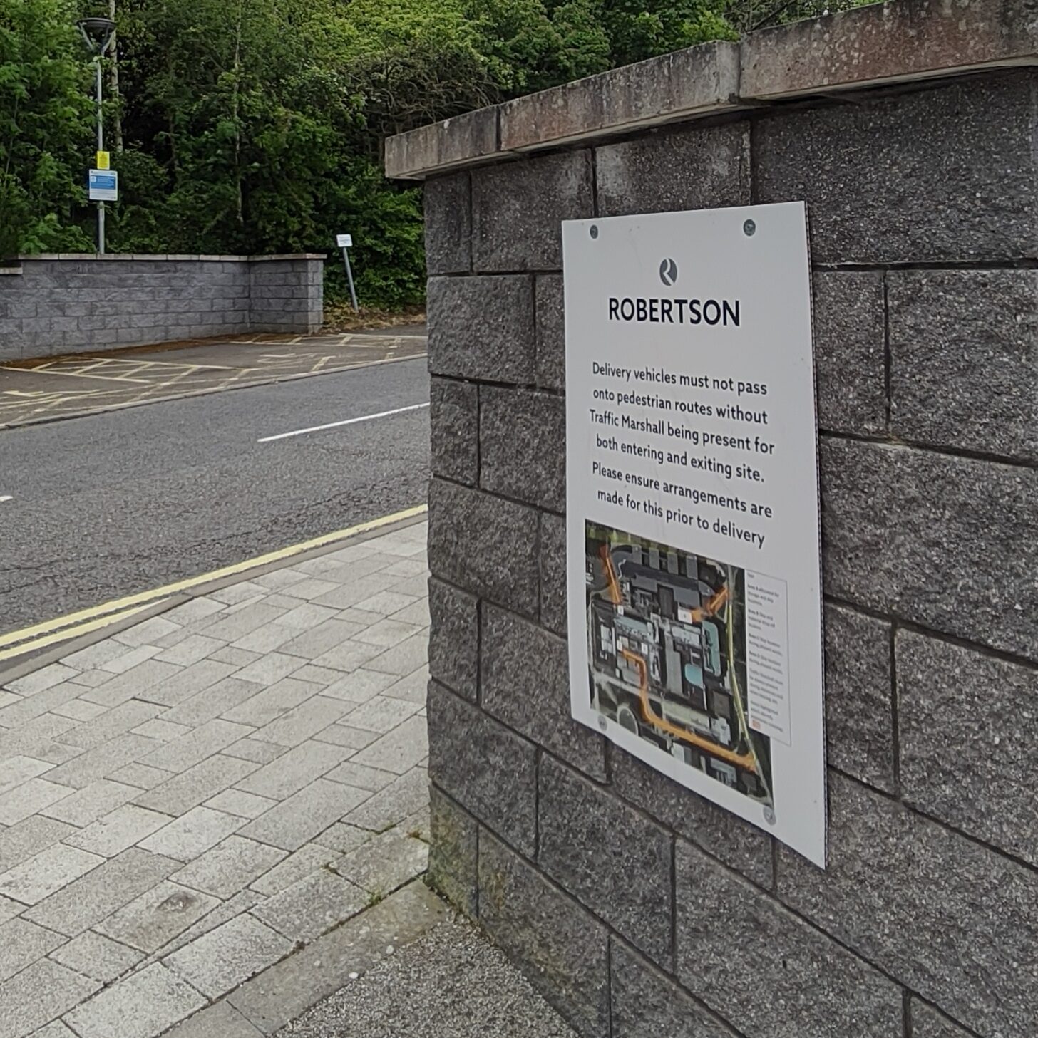 Stone wall on the right of the image with a sign titled "Robertson" with some explanatory text and a map.